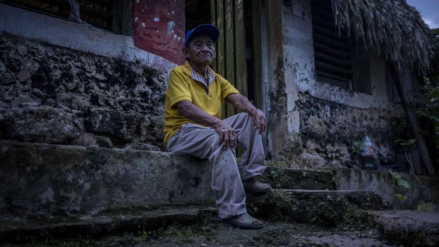 Comunidad maya: hombre en el portal de su casa tradicional